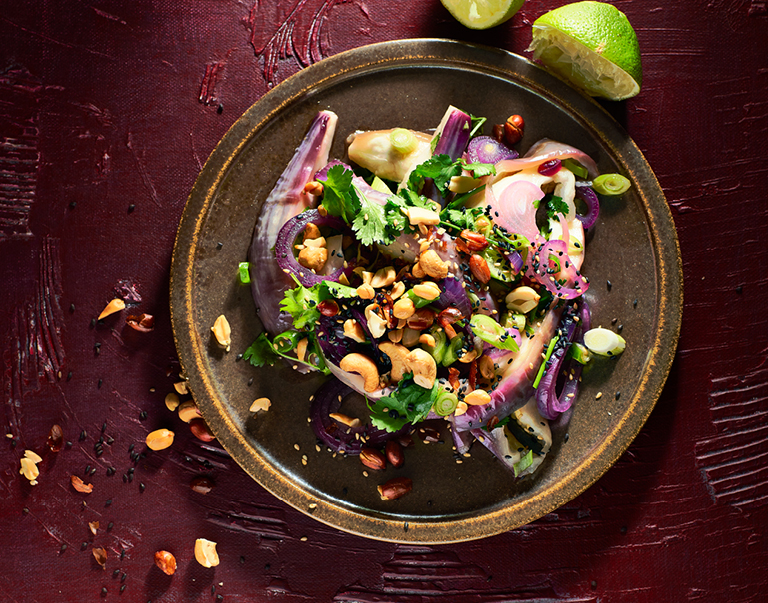 Simpel en snel: een salade van gestoomde aubergine. ui en knoflook. De dressing bestaat uit sesamolie en limoensap, de garnering uit pinda’s, noten, zaden en koriander.